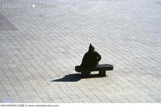 Hooded figure sitting alone on bench